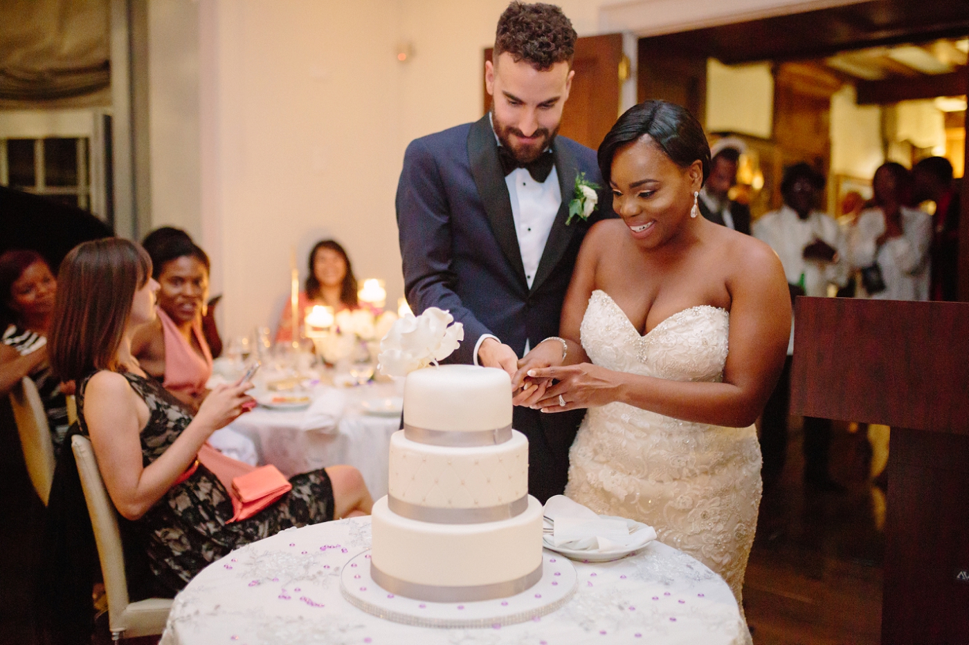 black bride and white groom cutting wedding cake at estates of sunnybrook