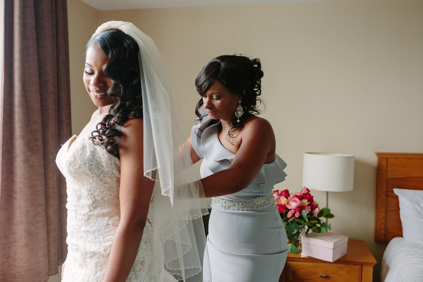 Mom helping bride put on wedding dress