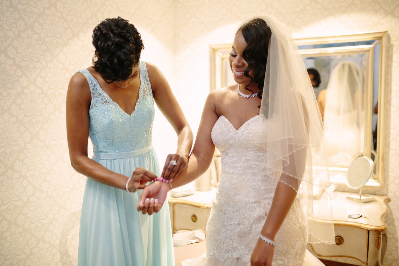 bridemaid helping to put on bridal jewelry