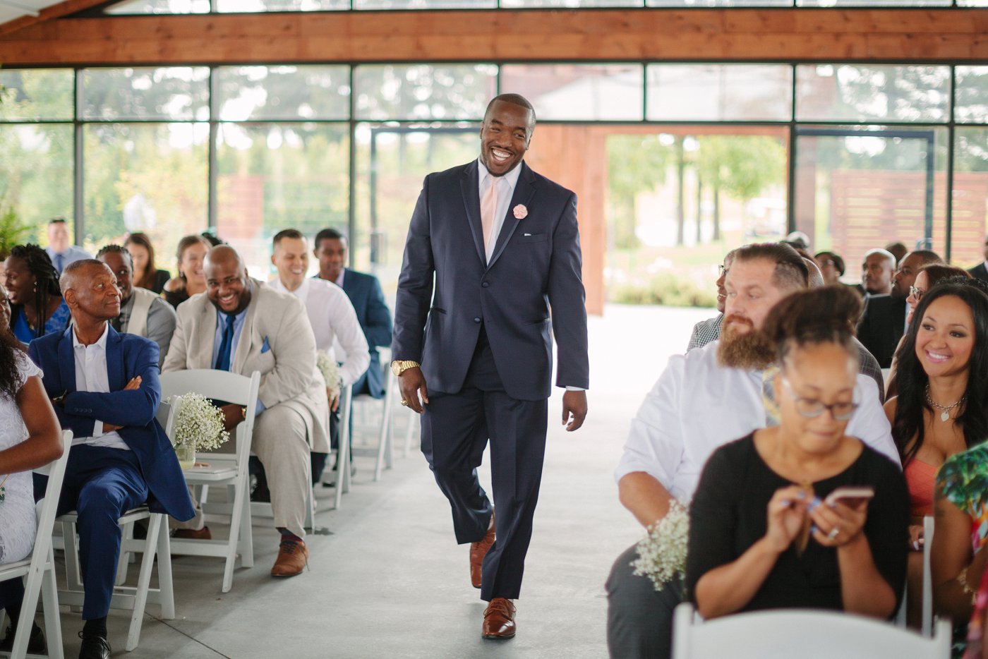 smiling groom walking down the aisle