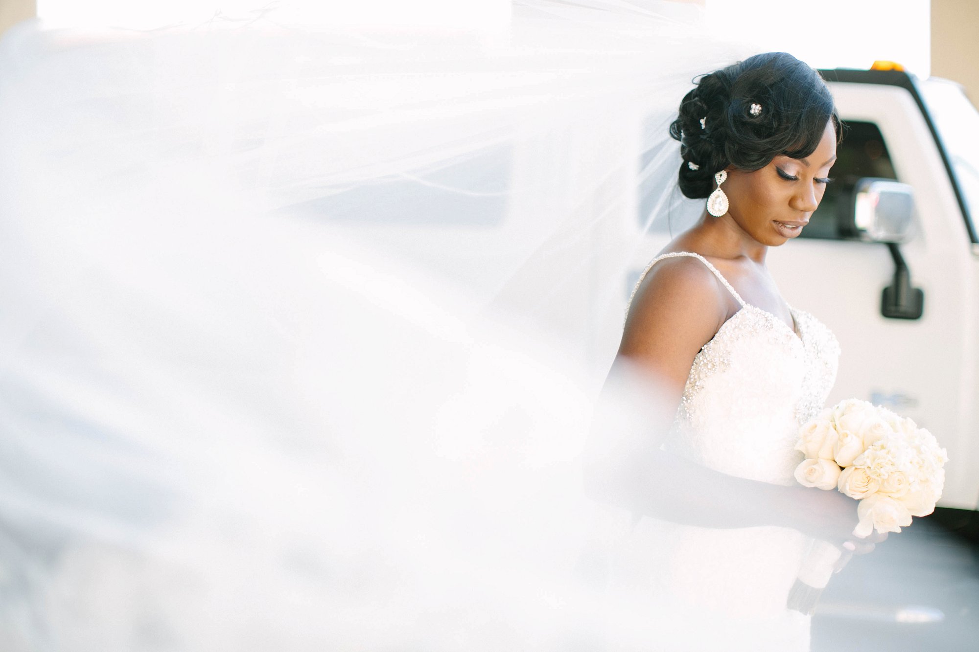 African bride with long veil and white rose bouquet