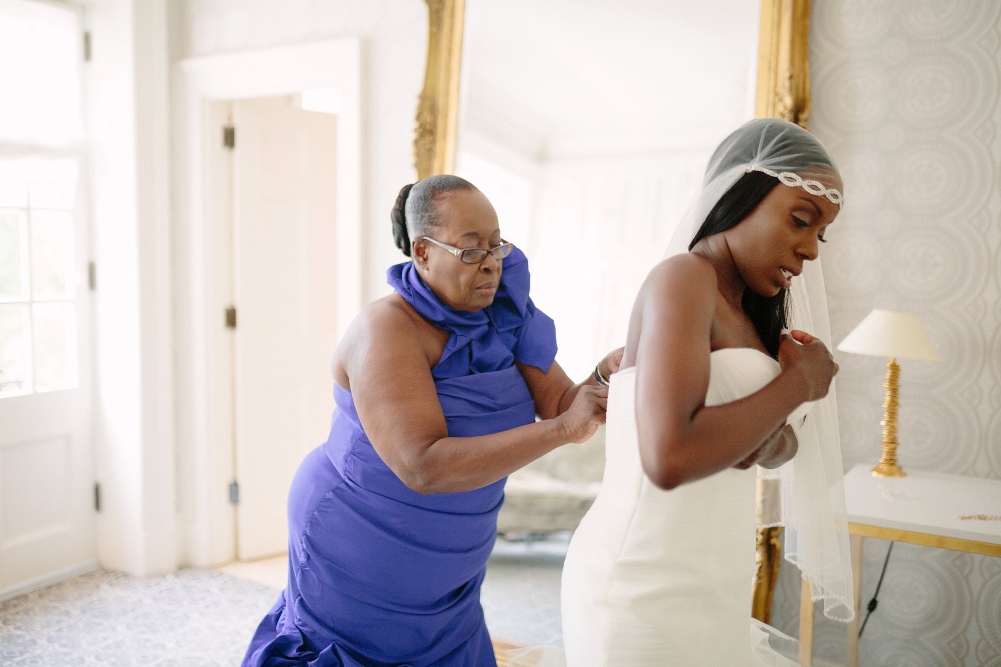 mother helps daughter with wedding dress