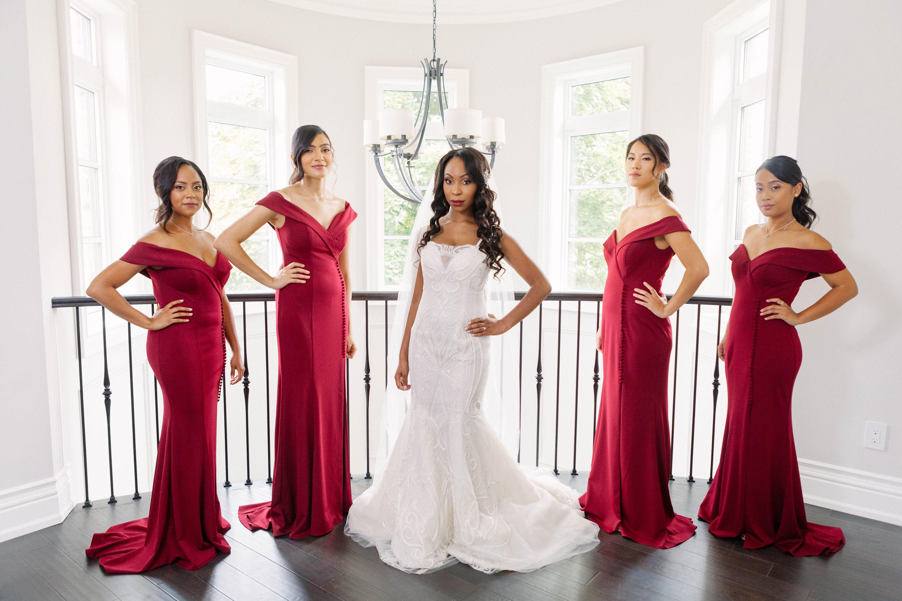 bridesmaids wearing red off-the-shoulder gowns with bride wearing ines di santo gown
