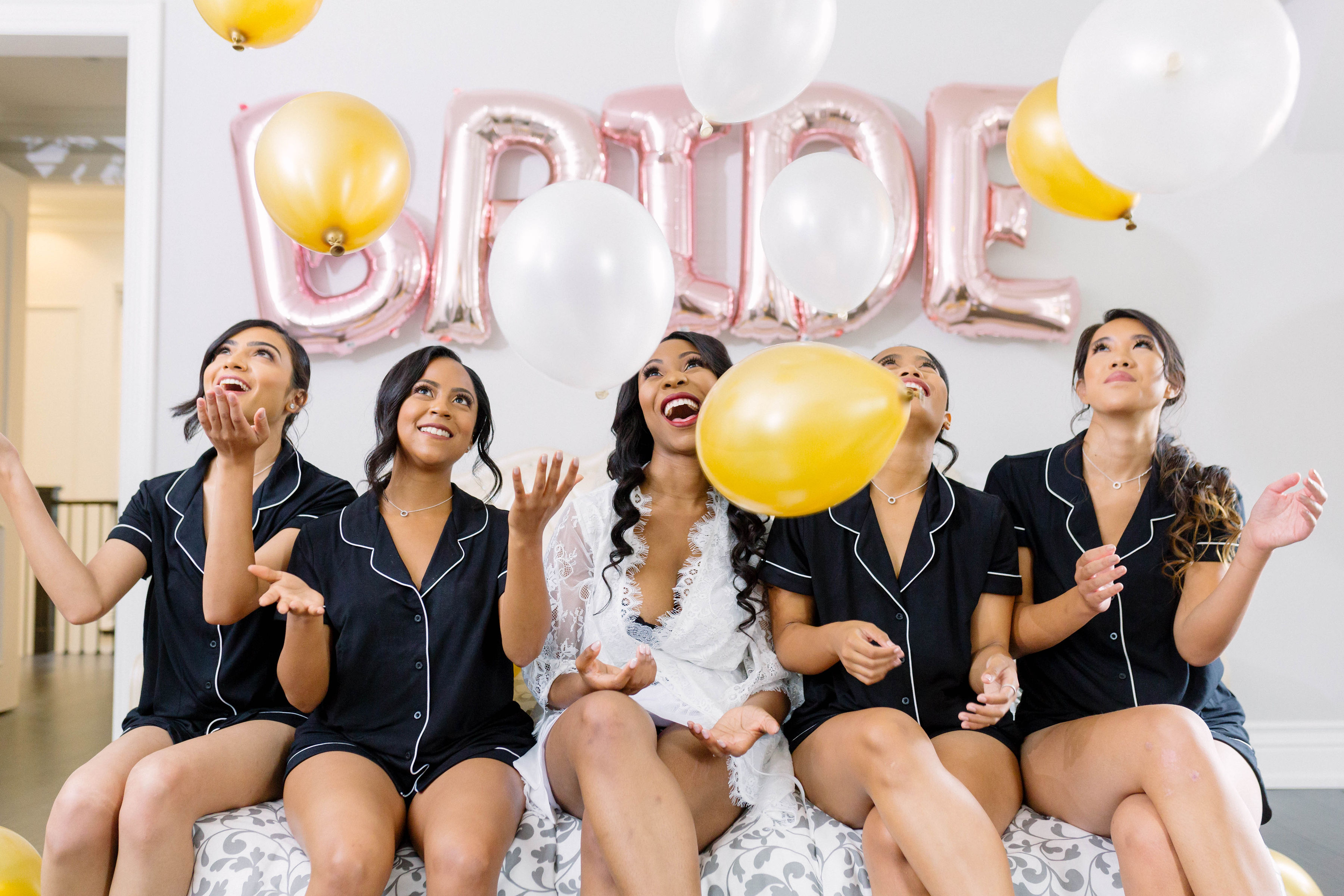 bride and bridemaids in matching short set with metallic bride balloons