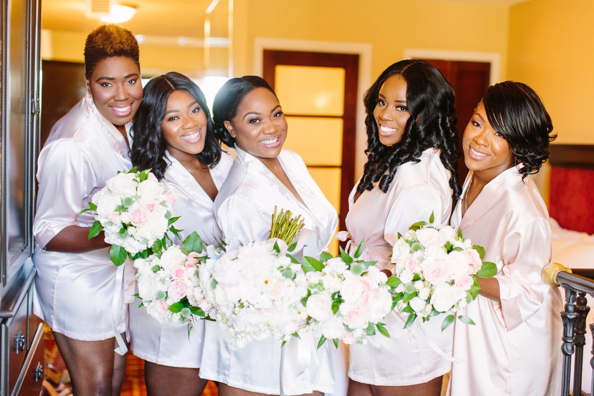 black and brown bridesmaids in blush satin robes