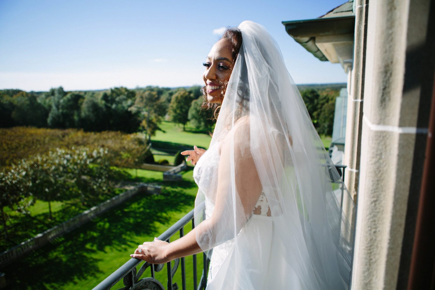 Bride looking over balcony at Oheka Castle in New York.