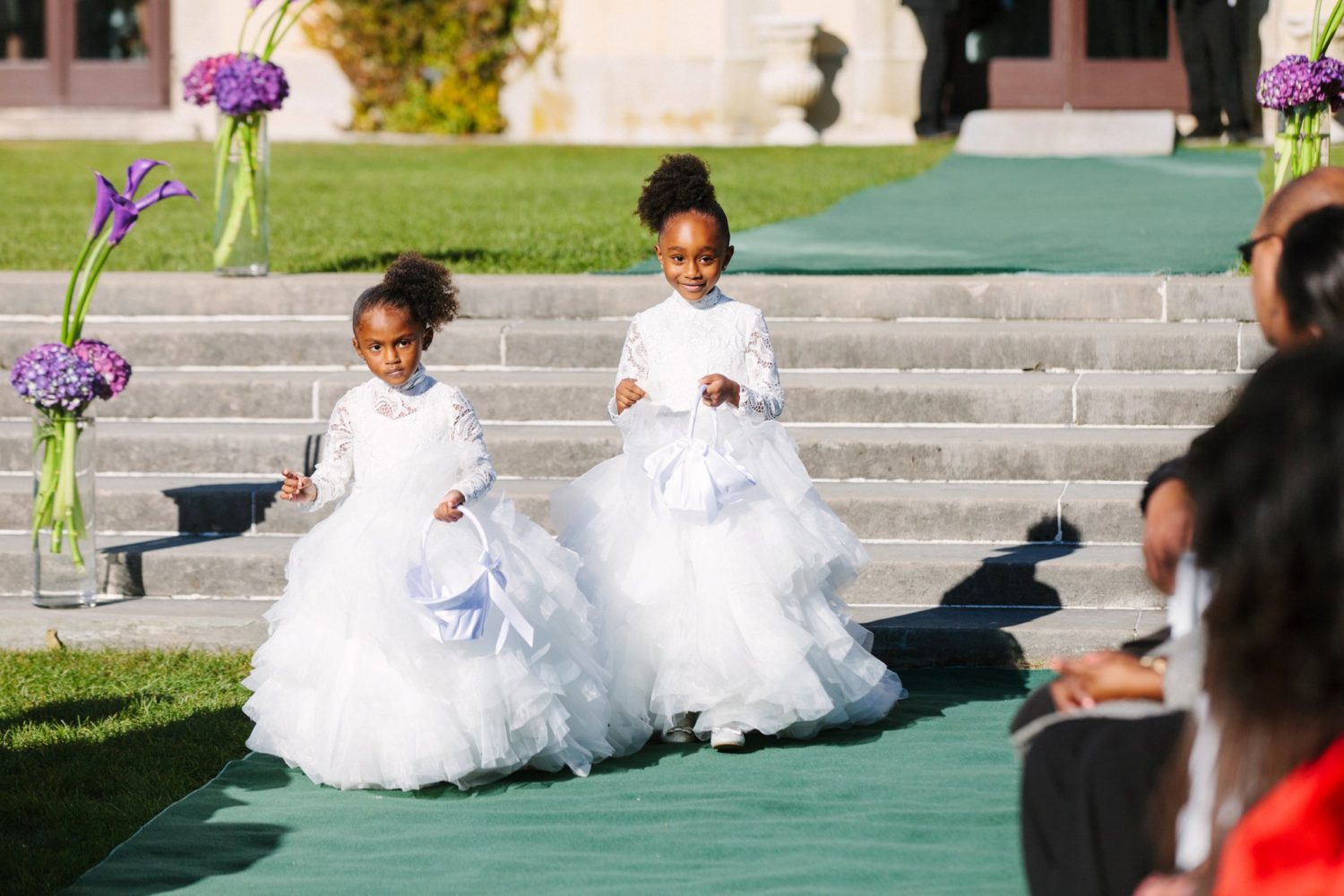 Flower girls walking down isle outside Oheka Castle.