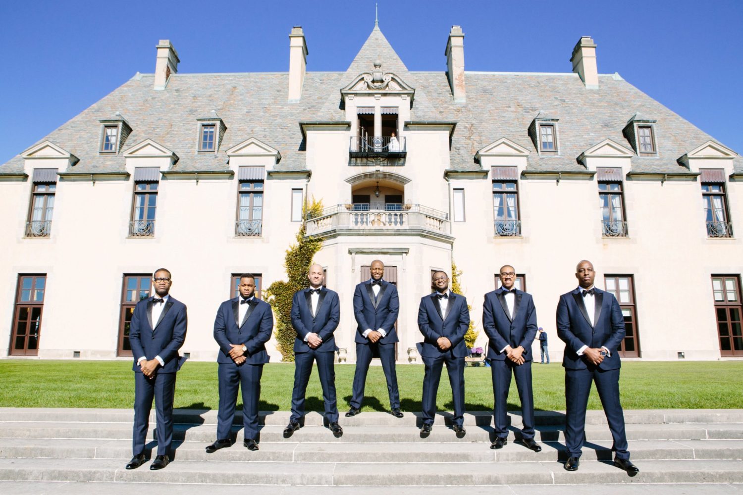 Groom and groomsmen standing on stairs outside of Oheka Castle.