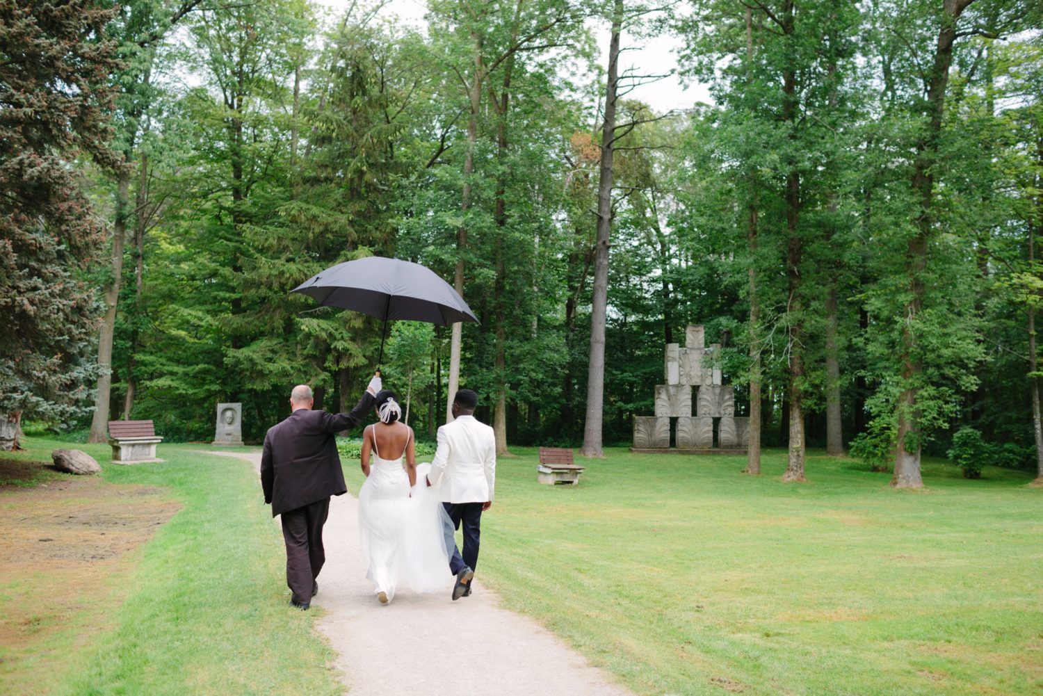 Wedding photography in rain, couple walking through a park.
