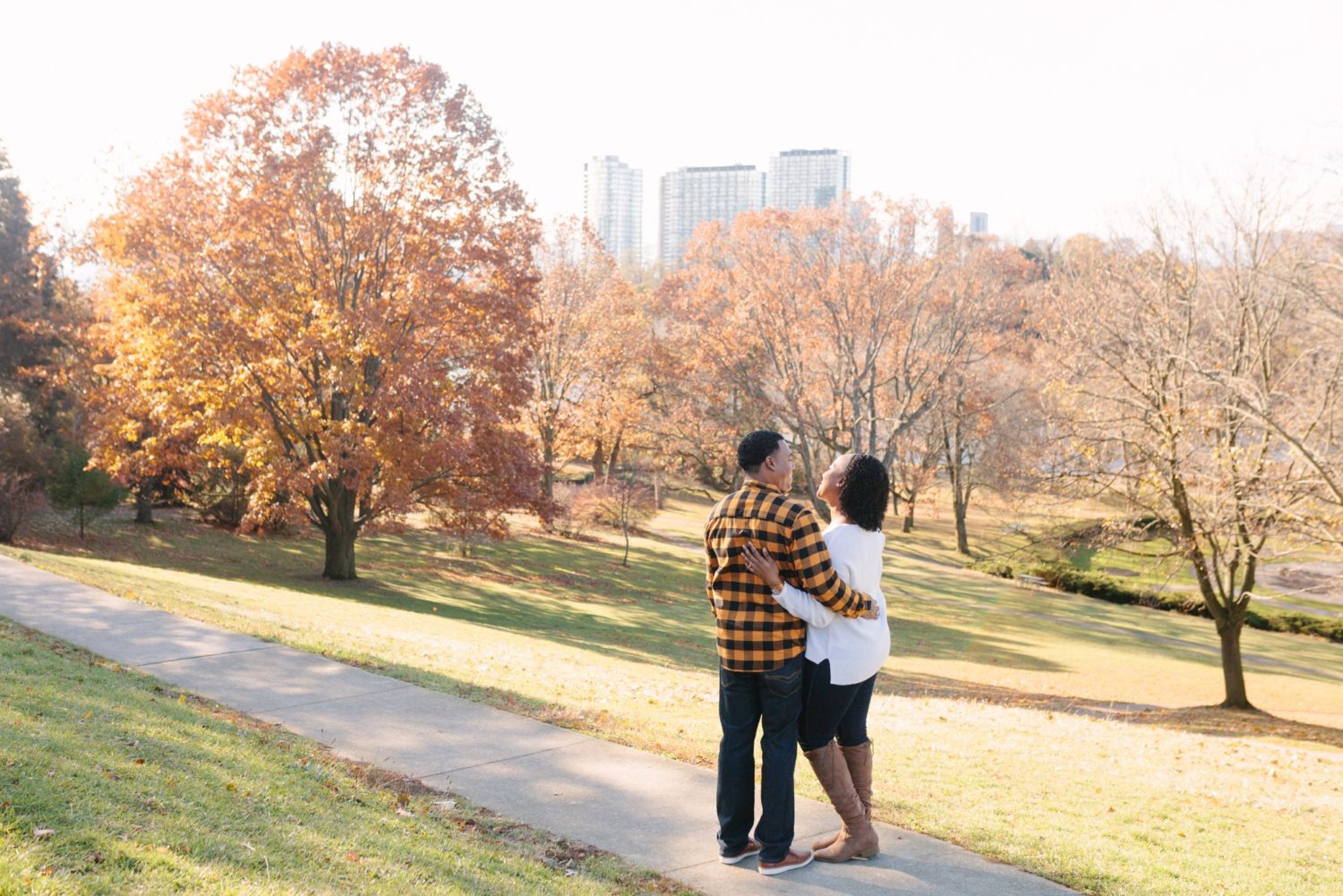 A couple with backs to camera looking at each other on a hill in High Park in the fall. 