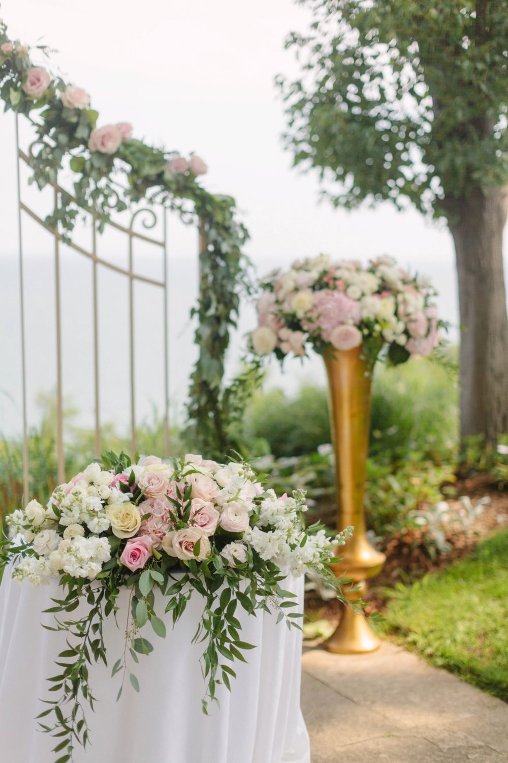 Roses and eucalyptus ceremony arch and centerpiece at outdoor wedding ceremony by Samantha Clarke Photography