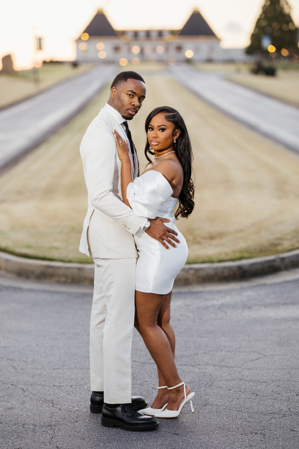 Engaged couple wearing stylish white outfits standing in front of Chateau Elan 